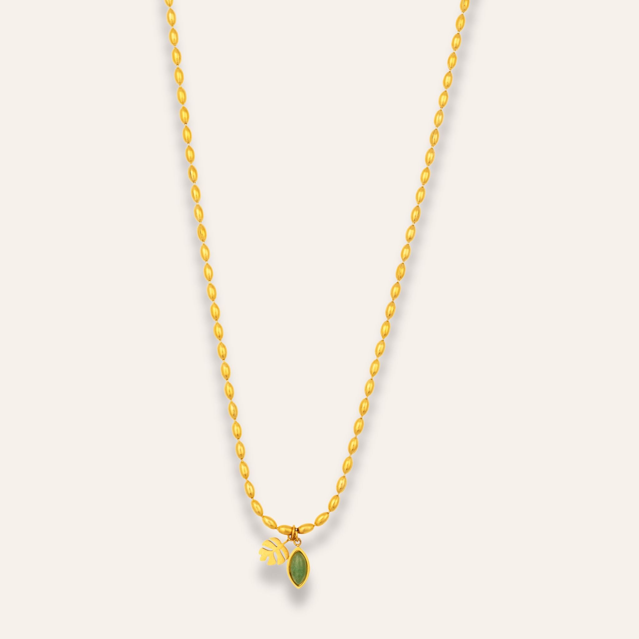 guldigt halsband med en grön sten och ett blad i hänge