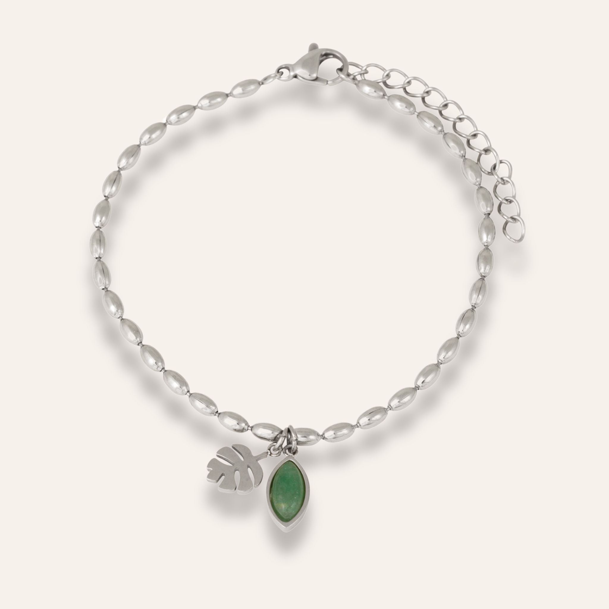 Silvrigt armband med en grön sten och ett blad i hänge