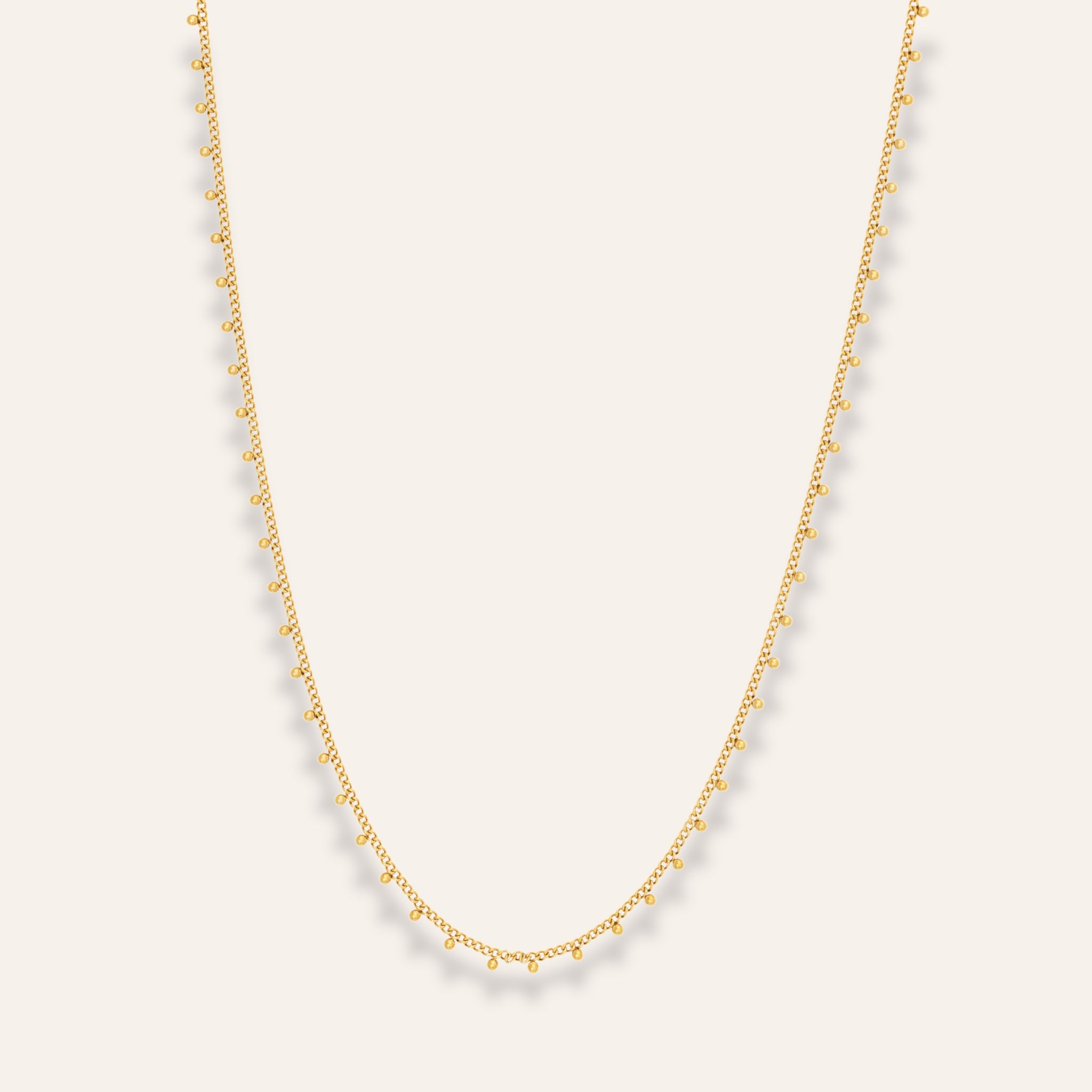 Ett elegant och tidlöst halsband tillverkat i rostfritt stål med 18-karats guldplätering. Halsbandet pryds av små pärlor runt hela kedjan