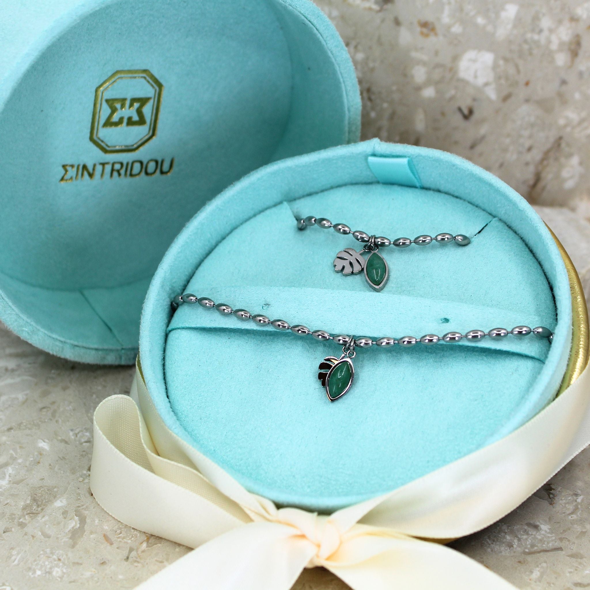 Ett smyckeset med green aventurine armband och halsband i färgen silver med en grön ädelsten, i en turkos sammet presentask