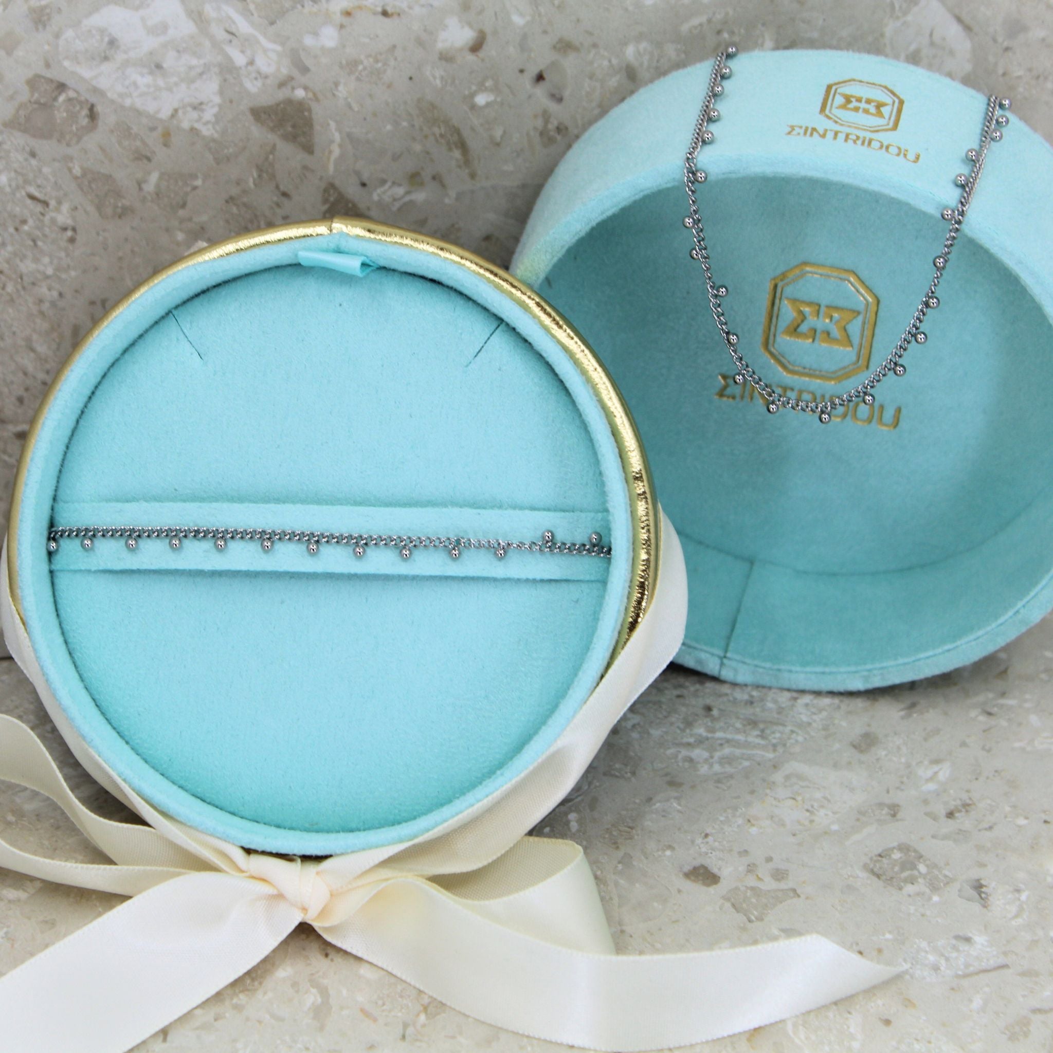 Ett smyckeset med Steel beaded halsband och armband i färgen silver, i en turkos sammet presentask