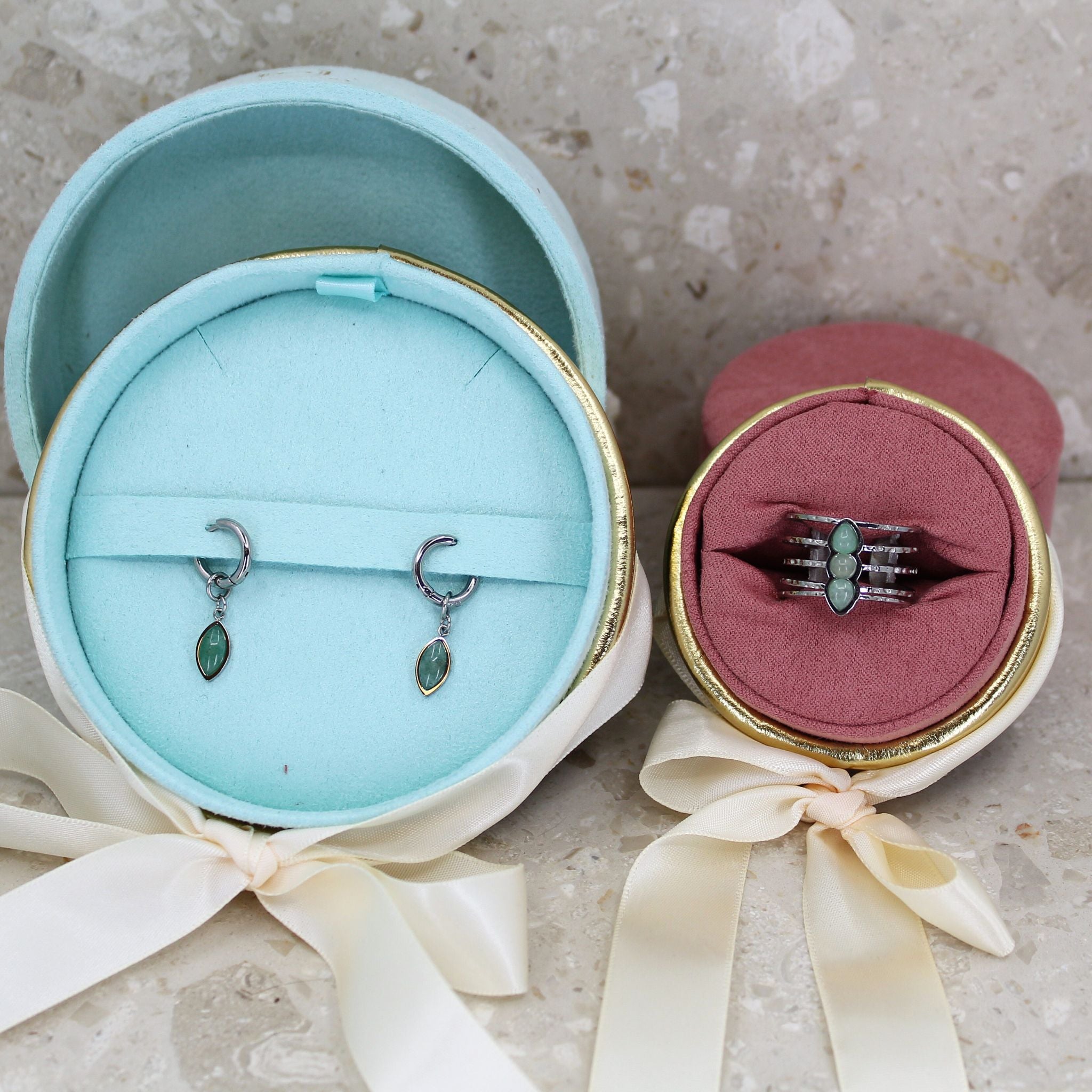 Ett smyckeset med green aventurine örhänge och ring i färgen silver med en grön ädelsten, i en turkos eller rosa sammet presentask